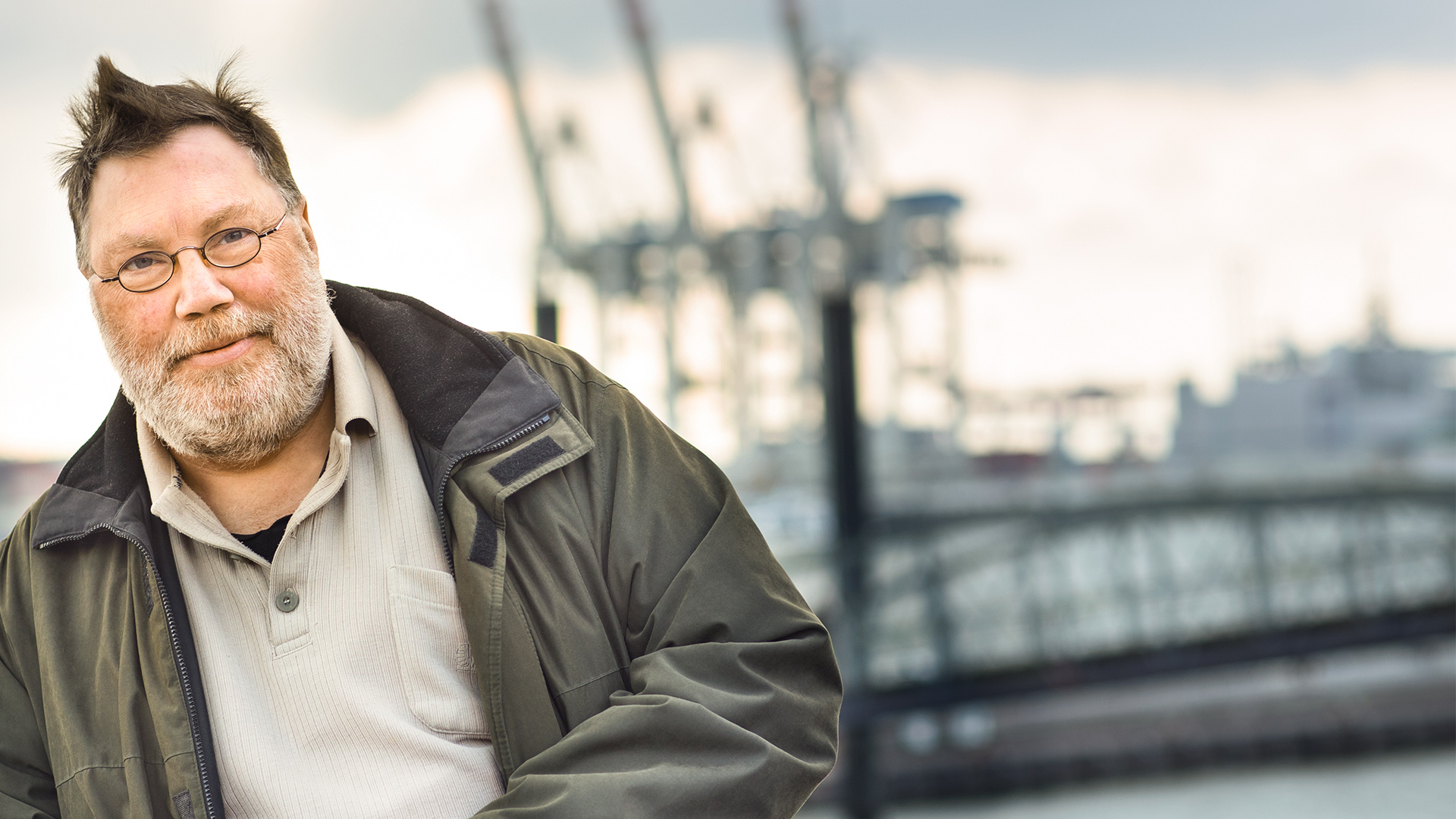 Mann schaut in die Kamera, im Hintergrund der Hamburger Hafen